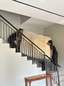 Two worker carefully carrying a furniture up the stairs